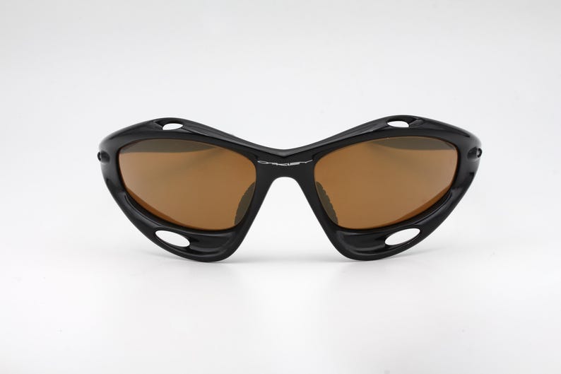 May include: Black sunglasses with brown lenses and a curved, wraparound design.