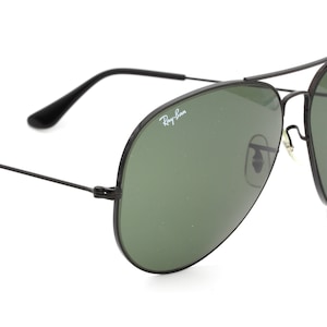 May include: Black aviator sunglasses with green lenses and Ray-Ban branding on the frame.