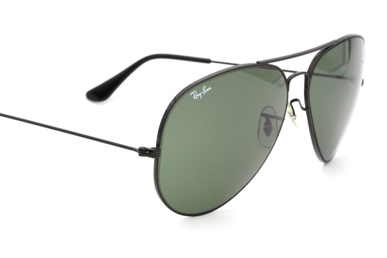 May include: Black aviator sunglasses with green lenses and Ray-Ban branding on the frame.