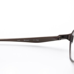 May include: Brown metal frame eyeglasses with clear lenses. The frame has the text "140 Brown 111-730" printed on the side.