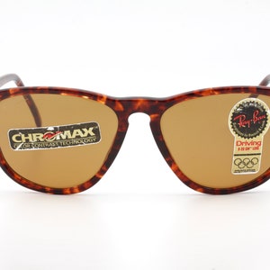 May include: Ray-Ban sunglasses with a tortoiseshell frame and brown lenses. The sunglasses have the "CHROMMAX" and "Ray-Ban Driving" labels attached. The lenses are a light brown color.