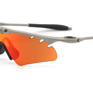 May include: A pair of gray wraparound sunglasses with orange lenses. The sunglasses have a sporty design and are made of a durable material.