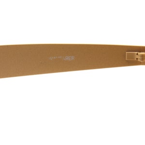 Puede incluir: Gafas de sol Wayfarer de color dorado con montura negra y lentes verdes. Las gafas est&aacute;n dobladas por la mitad y el logotipo de Wayfarer es visible en la patilla.