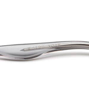 May include: Close-up of a silver-colored metal temple tip with the text "W1289 104V" engraved on it.