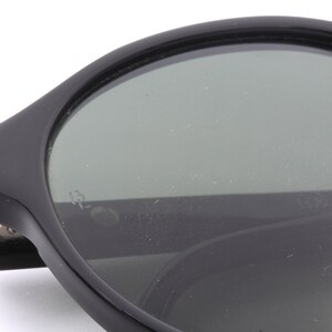 May include: Black round sunglasses with a dark gray lens. The sunglasses have a thick black frame.
