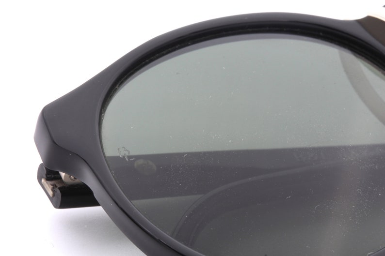 May include: Black round sunglasses with a dark gray lens. The sunglasses have a thick black frame.