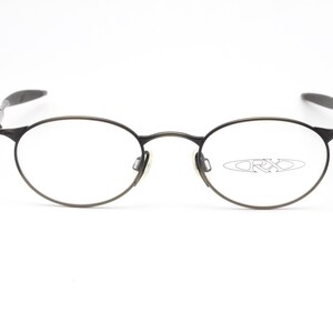 May include: A pair of round, silver-toned eyeglasses with a thin metal frame. The brand name "ORXO" is visible on the right lens.