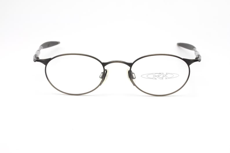 May include: A pair of round, silver-toned eyeglasses with a thin metal frame. The brand name "ORXO" is visible on the right lens.