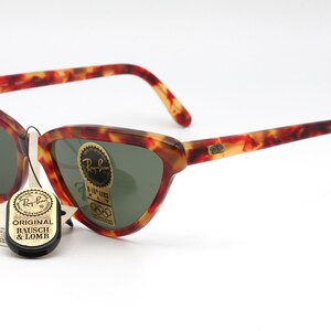 May include: Vintage Ray-Ban sunglasses with a tortoiseshell frame and green lenses. The sunglasses have a cat-eye shape and are in good condition. The sunglasses come with an original Bausch & Lomb tag.