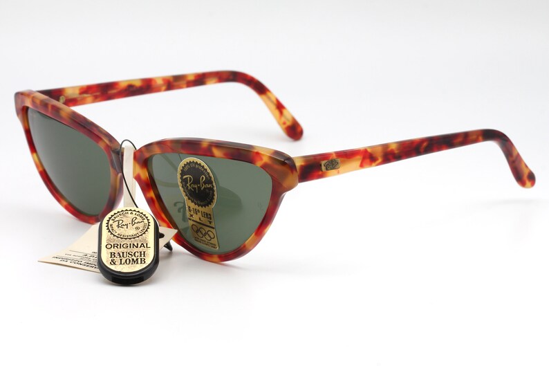 May include: Vintage Ray-Ban sunglasses with a tortoiseshell frame and green lenses. The sunglasses have a cat-eye shape and are in good condition. The sunglasses come with an original Bausch & Lomb tag.
