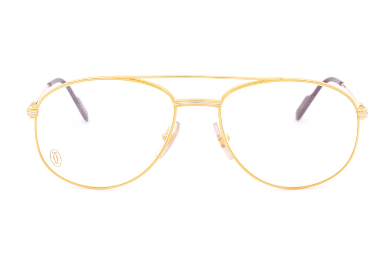 May include: Gold aviator eyeglasses with a thin gold frame and clear lenses. The Cartier logo is visible on the left lens.