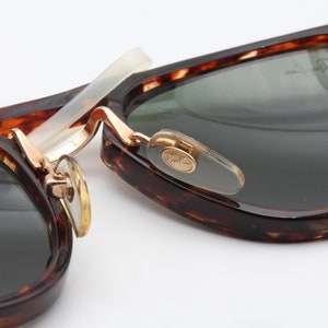 Op de afbeelding: Close-up van een paar schildpadzonnebrillen met gouden accenten. De zonnebril heeft een Ray-Ban-logo aan de zijkant.