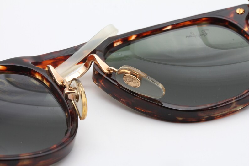 Op de afbeelding: Close-up van een paar schildpadzonnebrillen met gouden accenten. De zonnebril heeft een Ray-Ban-logo aan de zijkant.