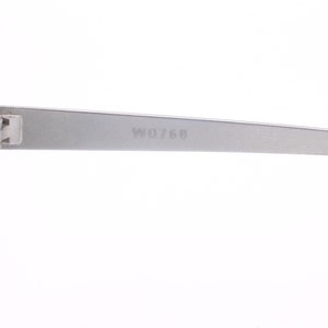 May include: Close-up of the silver metal arm of a pair of sunglasses. The arm is engraved with the number "W0768".
