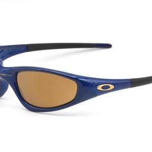 May include: Blue and black sunglasses with brown lenses. The sunglasses have a gold logo on the side.