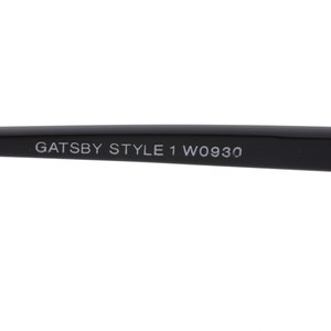 May include: Close-up of the black arm of a pair of glasses with the text "GATSBY STYLE 1 W0930" printed on it.