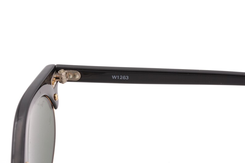 May include: Black sunglasses with a silver hinge and the text "W1263" on the arm.