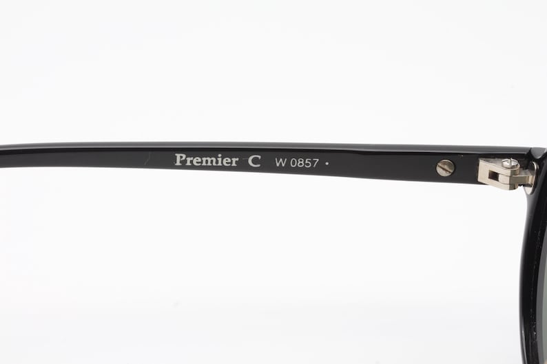 May include: Black plastic frame of a pair of glasses with the text "Premier C W 0857." printed on the side.