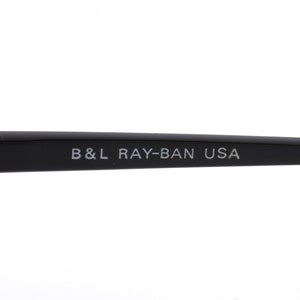 May include: Close-up of the black arm of a pair of Ray-Ban sunglasses with the text "B&L RAY-BAN USA" printed in white.