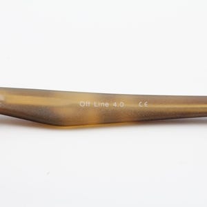 May include: Close-up of a portion of eyeglasses. The frame arm is a light brown color with the text "Off Line 4.0" and "CE" printed on the arm. The frame is made of a light brown material.