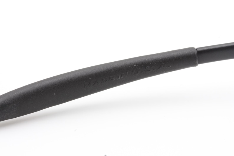 May include: Close-up of a black eyeglass arm with the text "MADE IN U.S.A." embossed on the side. The arm is curved and appears to be made of a matte material.