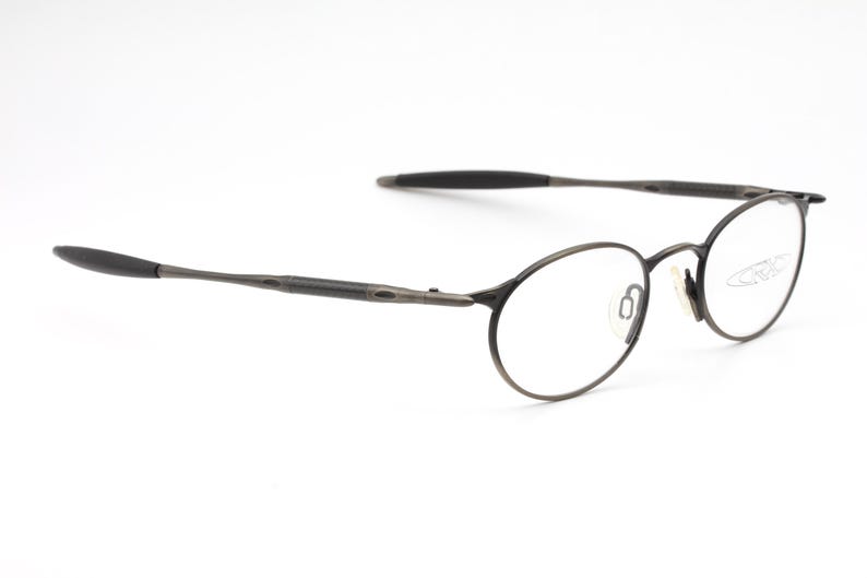 May include: A pair of round, black metal eyeglasses with thin frames. The glasses have a subtle, almost brushed, finish.