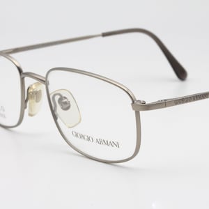 May include: Silver-toned metal eyeglasses with a rectangular frame and Giorgio Armani branding on the arm.