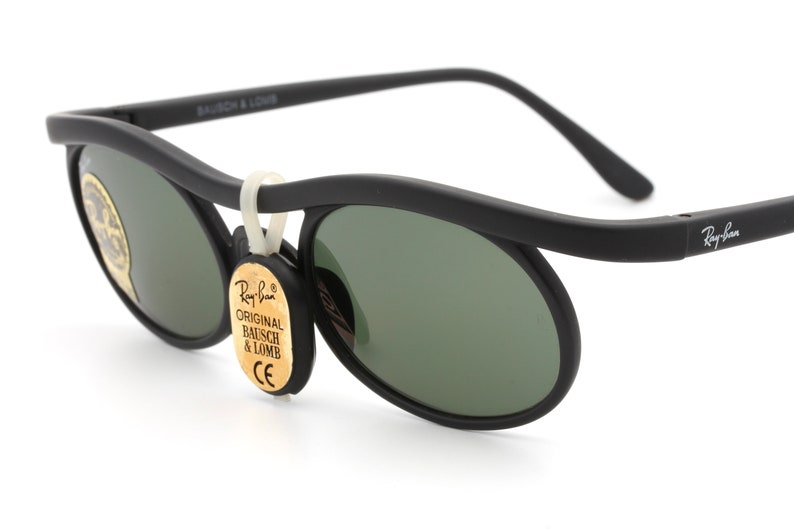 May include: Black Ray-Ban sunglasses with green lenses and a gold tag that reads "Original Bausch & Lomb".