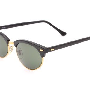 May include: Black sunglasses with green lenses and gold accents. The sunglasses have a classic aviator style.