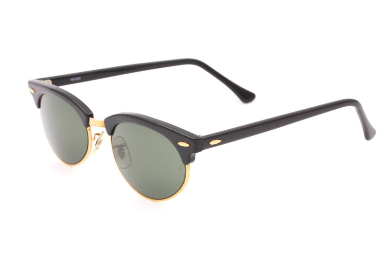 May include: Black sunglasses with green lenses and gold accents. The sunglasses have a classic aviator style.