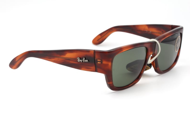 Puede incluir: Gafas de sol Ray-Ban con estampado de carey y lentes verdes. Las gafas tienen una montura rectangular y un dise&ntilde;o cl&aacute;sico. El logotipo de Ray-Ban es visible en la patilla. Una etiqueta blanca est&aacute; adjunta.