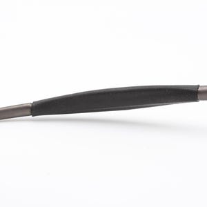 May include: Close-up of the temple arm of a pair of eyeglasses. The arm is a dark gray color with a black rubber grip. The tip of the arm is a lighter gray color.