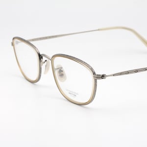 May include: Silver-toned eyeglasses with a rectangular frame and clear lenses. The temples have a decorative design. The glasses are set against a white background.