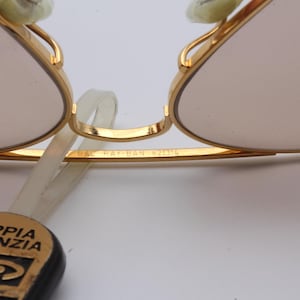 May include: Close-up of gold-tone aviator sunglasses with a brown lens. The sunglasses have the text "B&L Ray-Ban 6211" engraved on the frame.