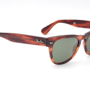 May include: Brown tortoiseshell Ray-Ban sunglasses with green lenses.