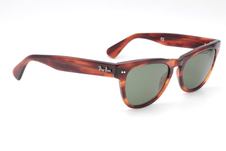May include: Brown tortoiseshell Ray-Ban sunglasses with green lenses.
