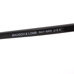 May include: Black Ray-Ban sunglasses with a metal hinge and the text "BAUSCH & LOMB RAY-BAN U.S.A." printed on the arm.
