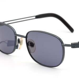 Può includere: Un paio di occhiali da sole aviator in metallo nero con lenti grigio scuro. Gli occhiali hanno un design semplice ed elegante.