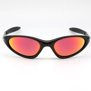 Può includere: Occhiali da sole neri con montatura curva e lenti rosso-arancio. Design sportivo. Le lenti presentano un effetto sfumato, dal rosso all'arancione. Adatti per attività all'aperto.