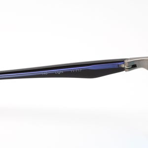 May include: Close-up of a pair of eyeglasses with a silver frame and blue lenses. The temples are black with the text "140 Light 11-717". The lenses are a light blue color.