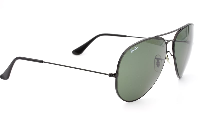 May include: Black aviator sunglasses with green lenses and Ray-Ban branding on the frame.