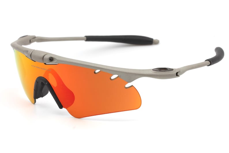 May include: A pair of gray wraparound sunglasses with orange lenses. The sunglasses have a black rubber nose piece and ear pieces.