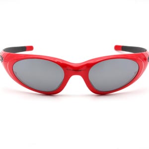 Puede incluir: Gafas de sol rojas con montura curva y lentes grises.