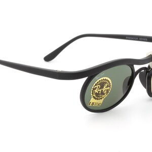May include: Black Ray-Ban Predator Series sunglasses with green lenses and a gold label that says "Ray-Ban Original Wayfarer 11003"