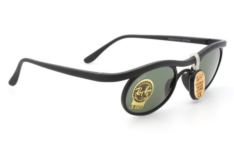 May include: Black Ray-Ban Predator Series sunglasses with green lenses and a gold label that says "Ray-Ban Original Wayfarer 11003"
