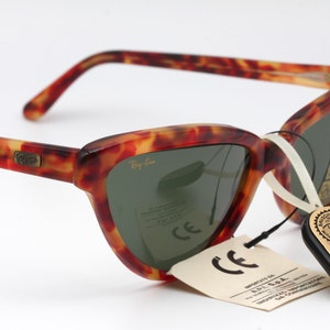 May include: Tortoiseshell Ray-Ban sunglasses with green lenses. The sunglasses have a tag that reads "Original Bausch & Lomb".