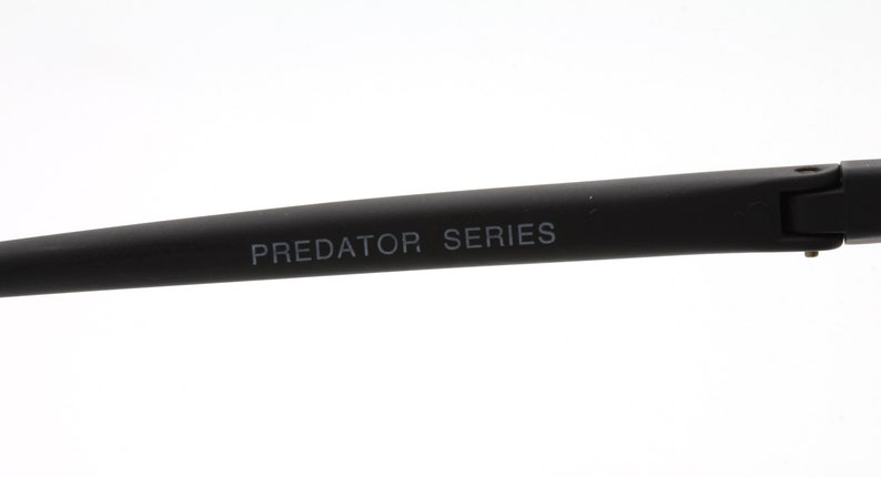 May include: Close-up of the black arm of a pair of glasses with the text "PREDATOR SERIES" printed in white.