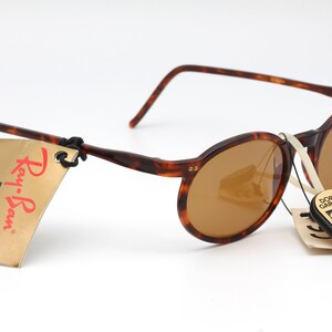 May include: Tortoise shell Ray-Ban Driving Series sunglasses with brown lenses. The sunglasses have a tag attached that reads "Ray-Ban Driving Series Sunglasses CHROMAX".