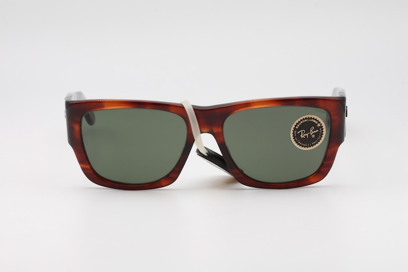 Puede incluir: Gafas de sol carey marr&oacute;n con lentes verdes. Las gafas de sol tienen una montura rectangular y una peque&ntilde;a pegatina en la lente derecha. Las gafas de sol son nuevas y tienen una etiqueta blanca.