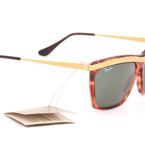 May include: Tortoise shell and gold Ray-Ban sunglasses with green lenses. The sunglasses have a gold metal band across the top of the frame.